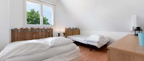 A bedroom with two beds, a window with a view of trees, and a wooden headboard.