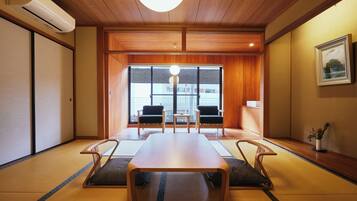 A traditional Japanese-style room with tatami flooring, a low wooden table, and two chairs.