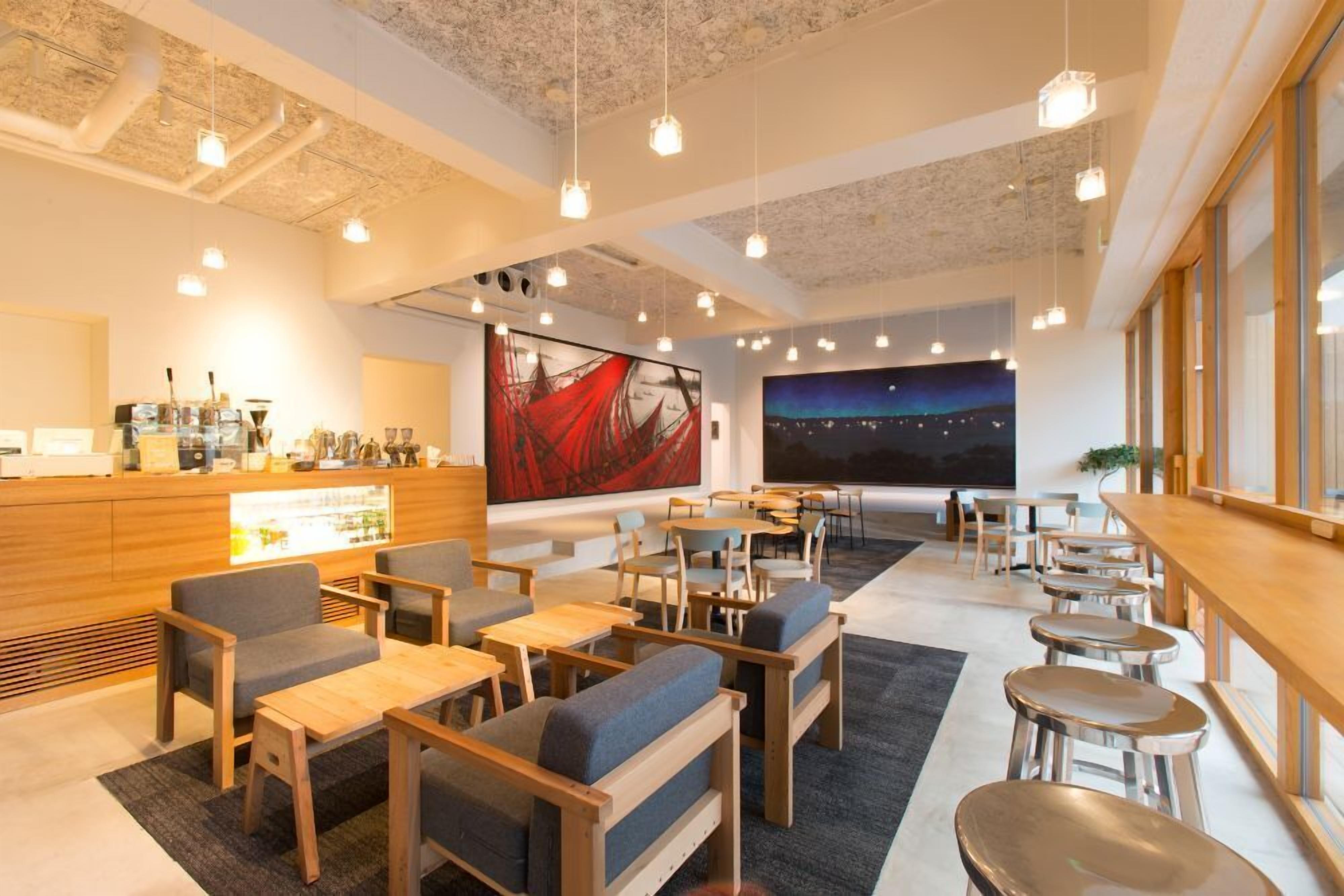 Een moderne hotel lobby met een bar, zithoeken en kunstwerken aan de muren.