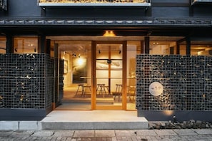A building entrance with glass doors, a seating area inside, and a sign with Japanese characters. - TSUCHIYA Kinosaki onsen (Toyooka)