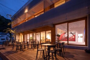 Um edifício moderno com terraço de madeira, área de estar externa e grandes janelas.
