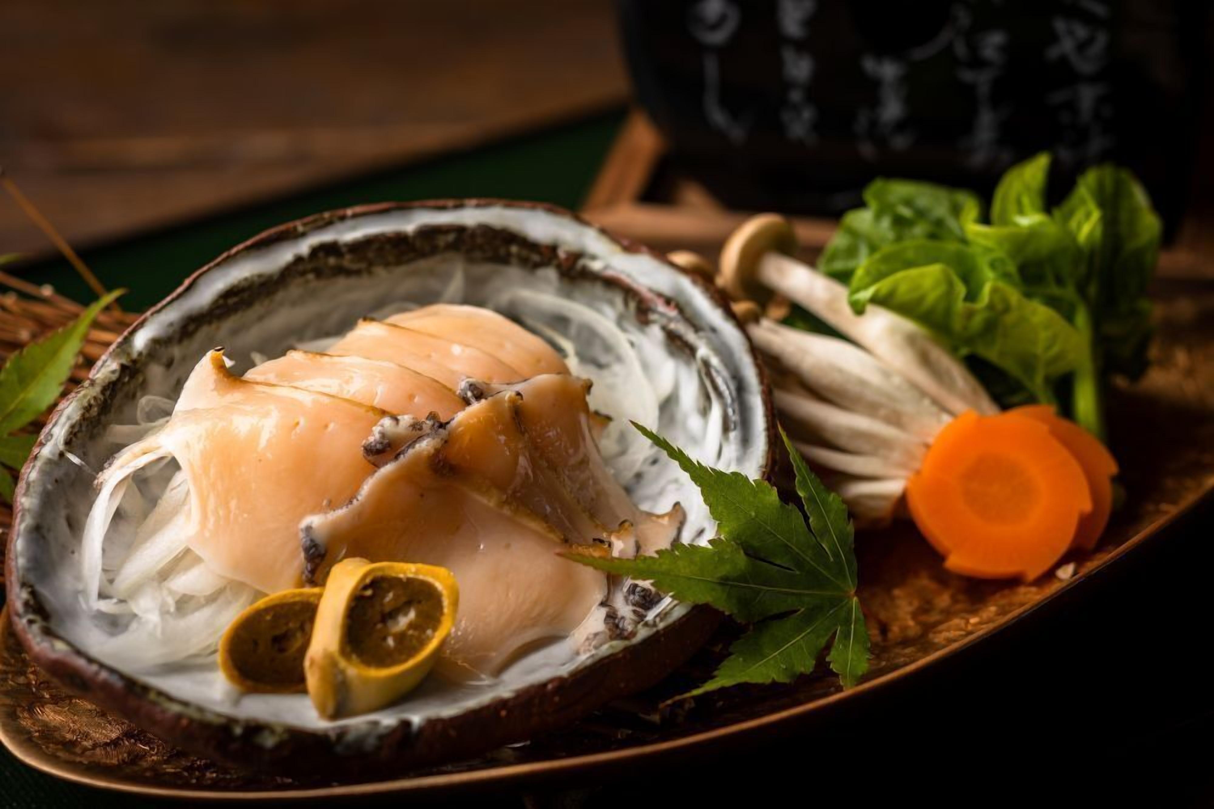 A dish with sliced fish on a plate, accompanied by vegetables and herbs.