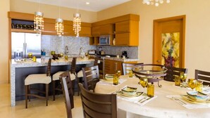 A modern kitchen with granite countertops, wooden cabinets, and a dining area with a round table set for six. - 2-Bedroom Suite at Garza Blanca, Puerto Vallarta (Puerto Vallarta)