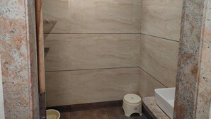 A small, tiled bathroom with a toilet, a sink, and a shower area. - Hotel Silvora Inn - Bhopal (Bhopal)