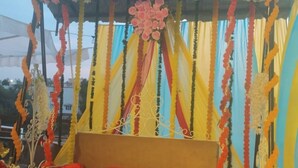 A bed with red bedding, a canopy with floral decorations, and a striped curtain backdrop. - Hotel Silvora Inn - Bhopal (Bhopal)