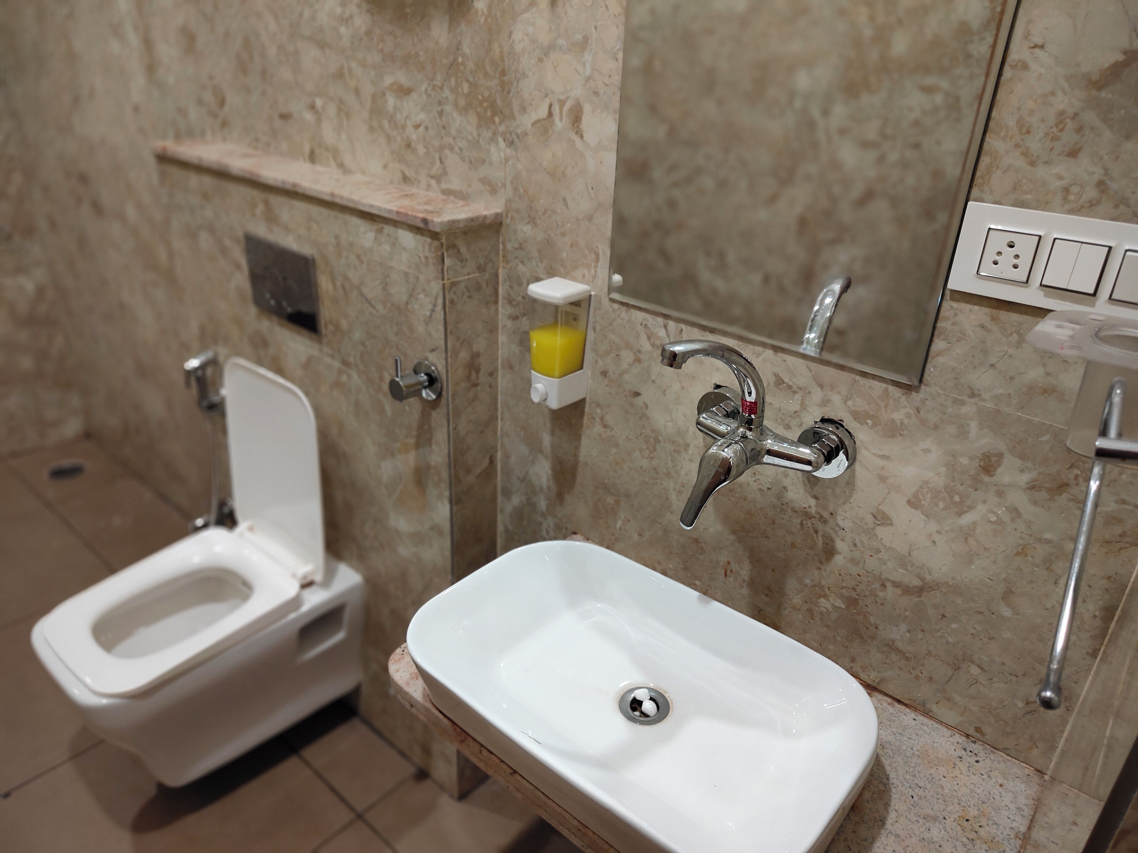 A bathroom with a toilet, sink, and a mirror.