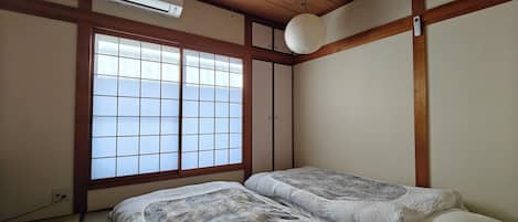 A traditional Japanese room with tatami flooring, a sliding shoji door, and a ceiling fan.