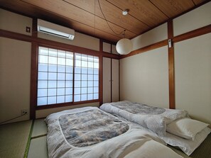 A traditional Japanese room with tatami flooring, a sliding shoji door, and a ceiling fan. - Funyado (Osaka)