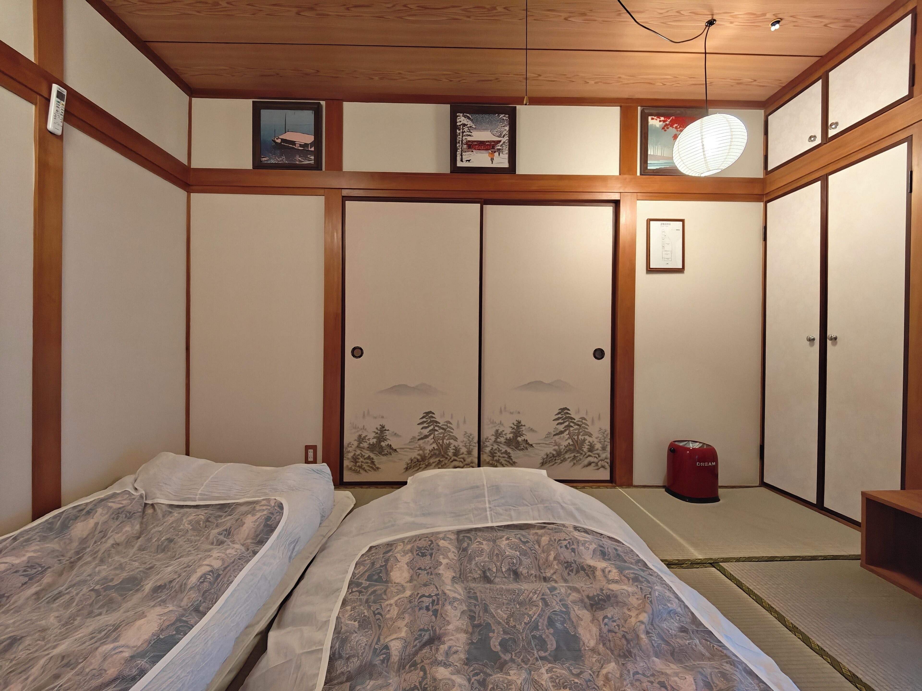 A traditional Japanese-style room with tatami flooring, a shoji screen door, and a futon bed.
