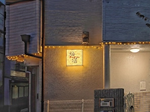 A building facade with a textured wall, a sign with foreign script, and a security gate. - Funyado (Osaka)