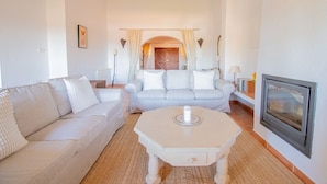 Una sala de estar con sofá, una mesa de centro, chimenea y una puerta que da a otra habitación.