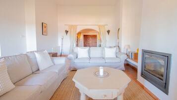 Una sala de estar con sofá, una mesa de centro, chimenea y una puerta que da a otra habitación.