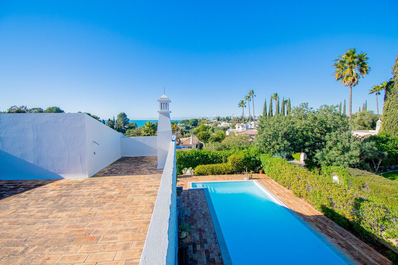 Una piscina en la azotea con vistas despejadas del paisaje circundante, incluyendo árboles y edificios al fondo.