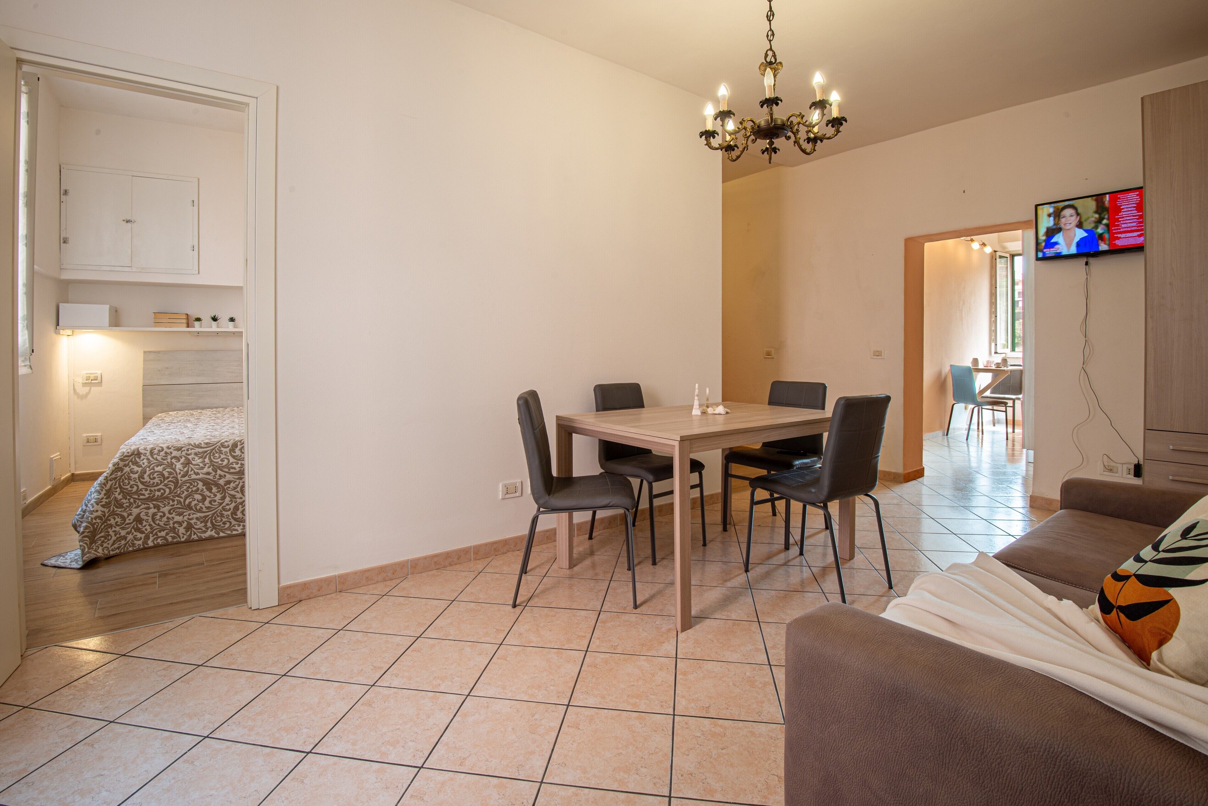 Ein Essbereich mit Tisch, Stühlen, einer Deckenleuchte, einem Fernseher und einer Couch.