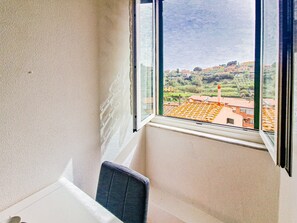 Una habitación con un ventanal grande, una silla y vistas a un pueblo con edificios y zonas verdes.