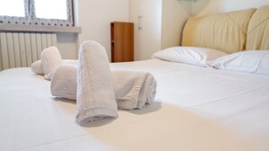 Un lit bien fait, avec des serviettes blanches pliées, une table de chevet en bois et une lampe de chevet.