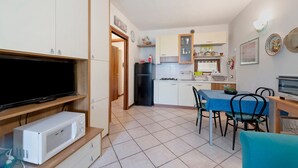 Une cuisine compacte équipée d’un four à micro-ondes, d’un réfrigérateur et d’un coin repas avec des chaises et une table.