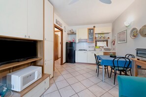 Una cocina compacta con microondas, refrigerador y comedor con sillas y una mesa.