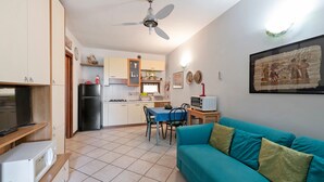 Un espace de vie compact comprenant un coin cuisine, un coin repas, un canapé et un ventilateur de plafond.