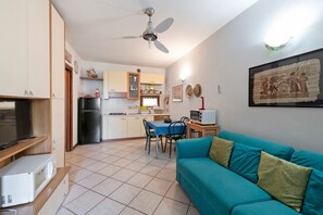 Un espacio habitable compacto con kitchenette, comedor, sofá y ventilador de techo.