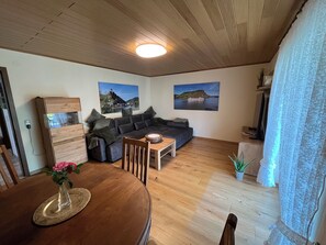 Un salon avec un plafond en bois, un canapé, une table basse et deux tableaux accrochés au mur.