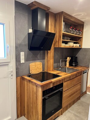 Une cuisine moderne dotée d’une cuisinière à gaz intégrée, d’un four et d’un plan de travail en bois.