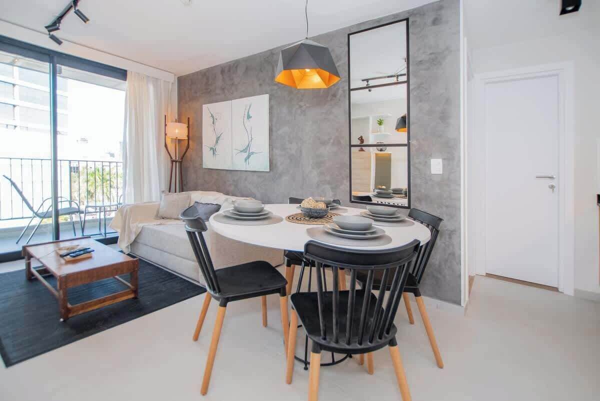 A modern dining area with a round table, black chairs, and a pendant light.