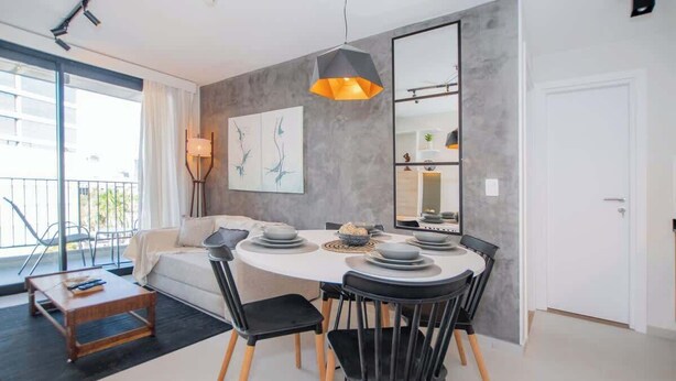 Een moderne eethoek met een ronde tafel, zwarte stoelen en een hanglamp.