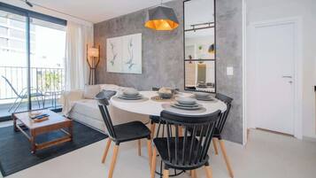 A modern dining area with a round table, black chairs, and a pendant light.