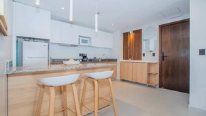 Een moderne keuken met witte kastjes, een houten aanrecht en twee barkrukken.