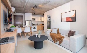 Un espacio habitable moderno con sofá, mesa de centro y zona de cocina.