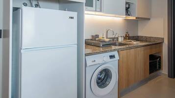 A compact kitchen with a washing machine, a refrigerator, and a microwave.