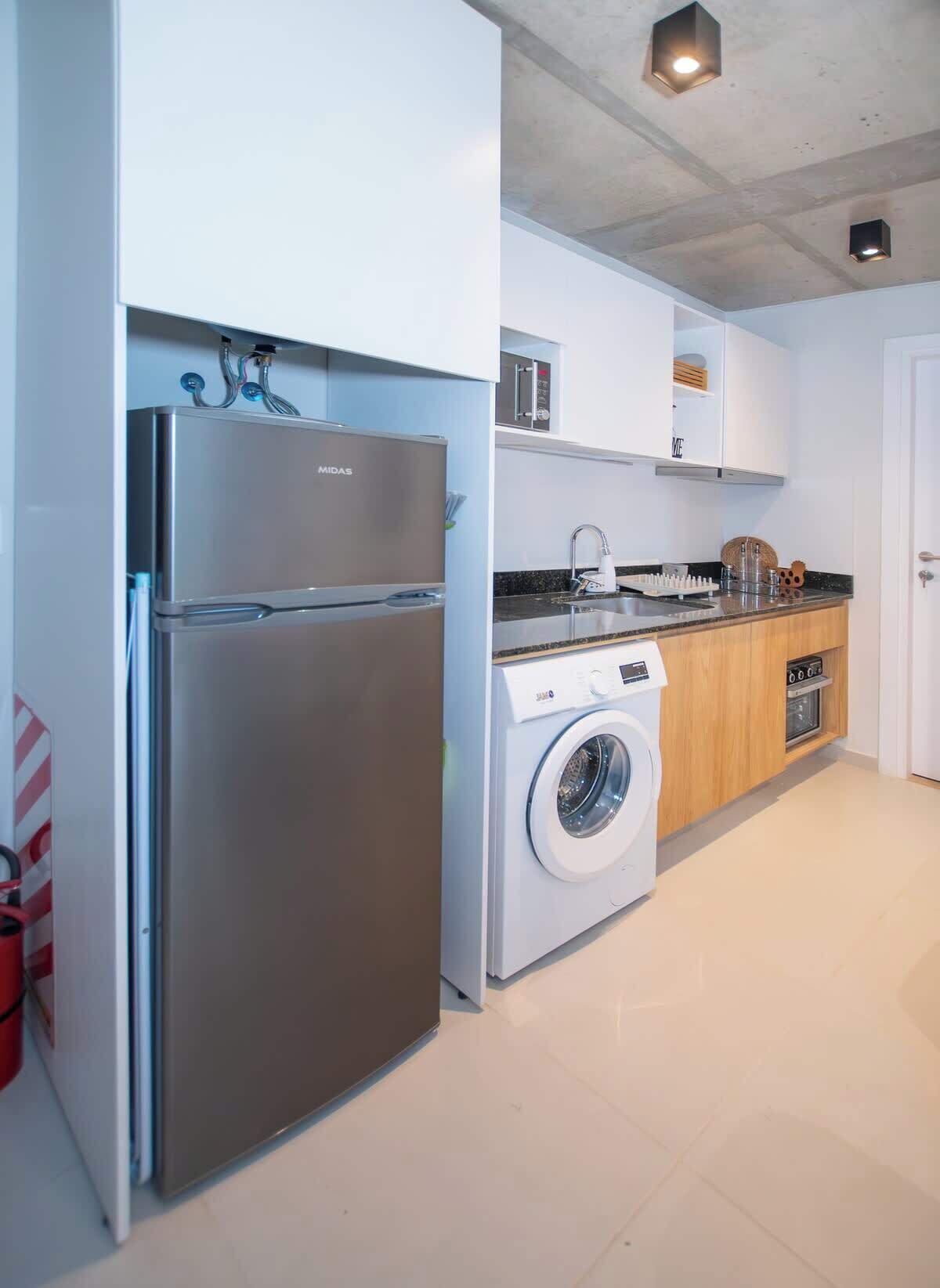A modern kitchen with a stainless steel refrigerator, a washing machine, and a built-in oven.