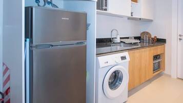 A modern kitchen with a stainless steel refrigerator, a washing machine, and a built-in oven.