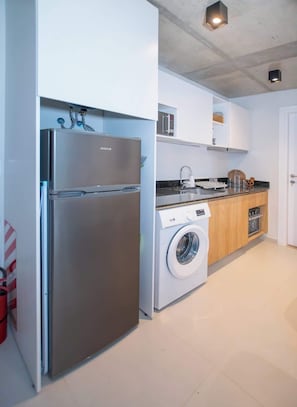 A modern kitchen with a stainless steel refrigerator, a washing machine, and a built-in oven. - Corporate Stays First del Sol (Asunción)