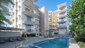 A hotel with a swimming pool, outdoor seating, and balconies. - Resort Studio Steps to Beach & Pool (Caloundra)