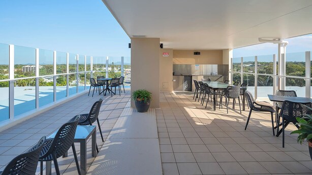A rooftop terrace with a dining area, a grill, and a view of the cityscape. - Resort Studio Steps to Beach & Pool (Caloundra)