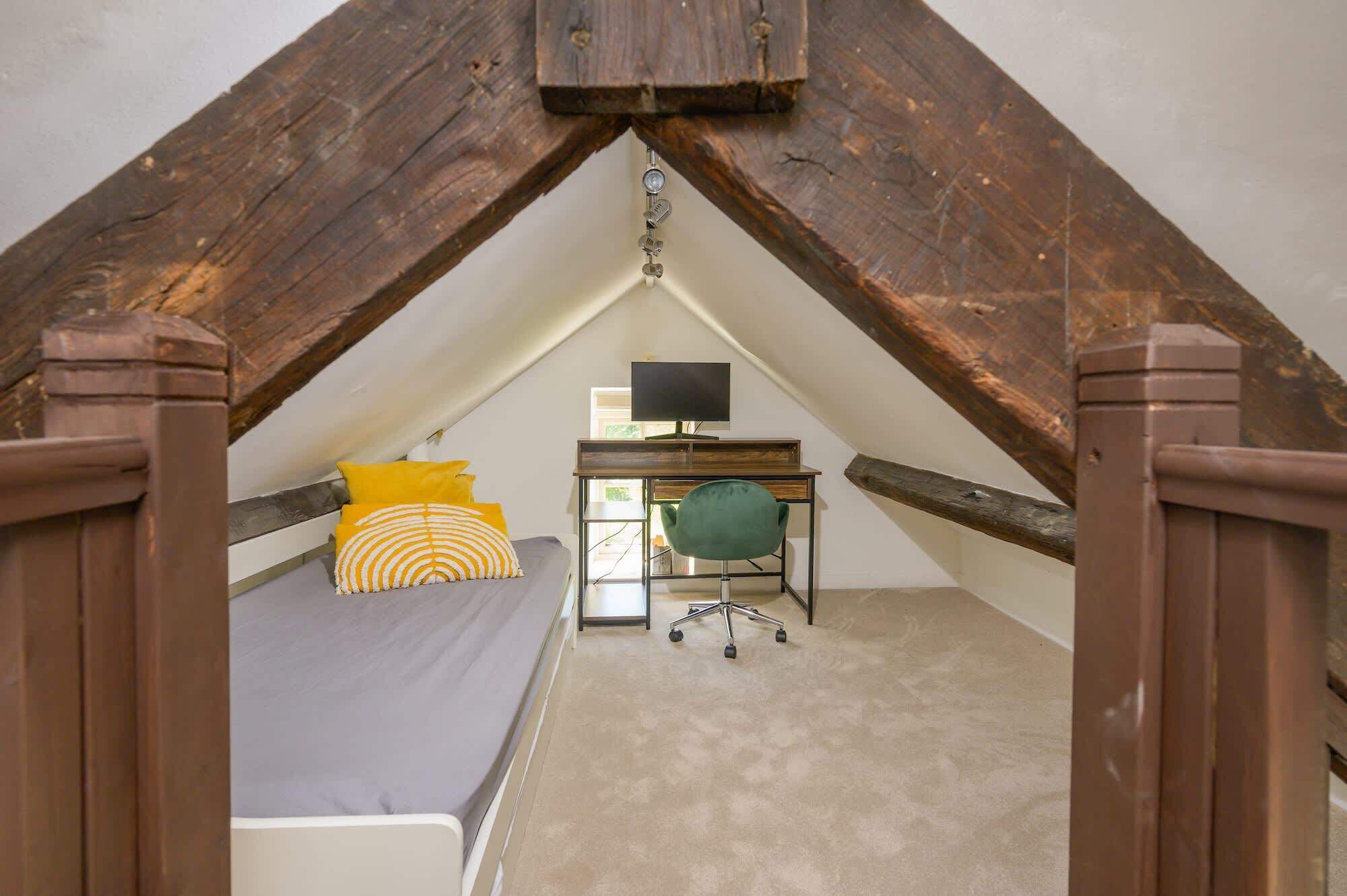 A bedroom with a bed, a desk, a chair, and a TV.