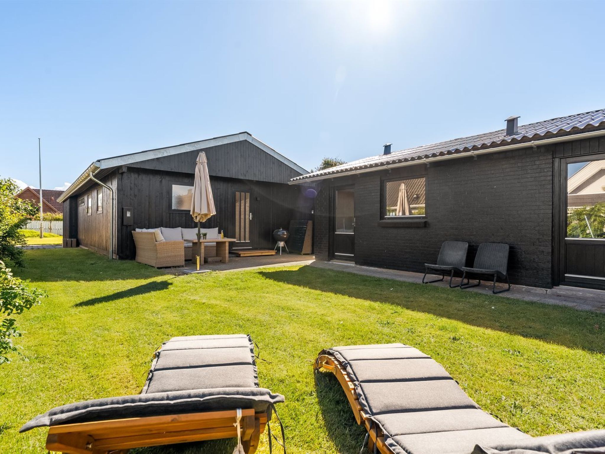 Una casa moderna con un patio grande, una zona de comedor y una barbacoa.