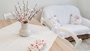 Ett matbord med en blomvas, en tallrik med mat och en vit soffa med blommiga kuddar.