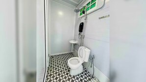 Ein kleines, kompaktes Badezimmer mit Toilette, Waschbecken und Dusche.