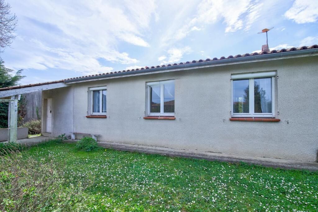 Un bâtiment d’un seul étage, doté de trois fenêtres, d’un toit plat et d’une cour gazonnée.