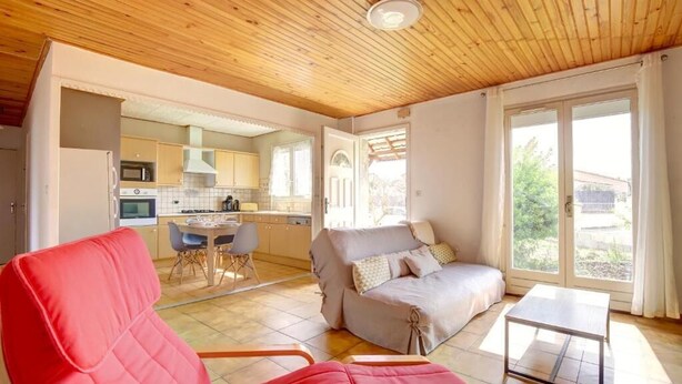 A modern interior with a wooden ceiling, a dining area, a sofa, and a sliding glass door leading to a garden. - The Van Gogh House: 3 bedrooms, 4 beds, and easy parking (Tournefeuille)