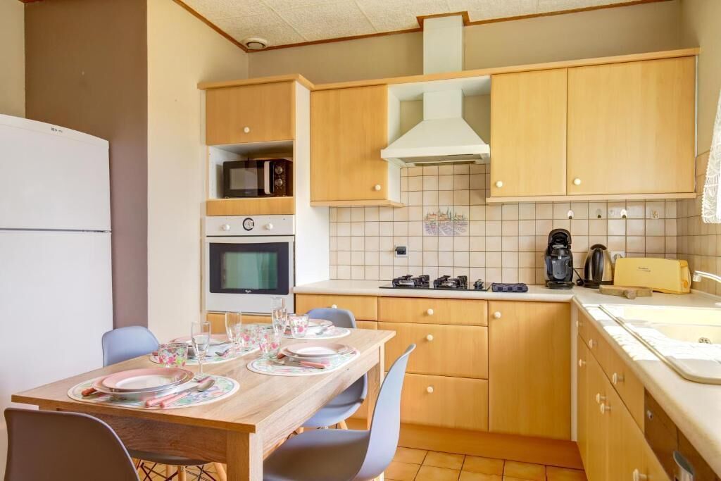 Una cocina compacta con armarios de madera, microondas, horno, cocina a gas y un lavamanos.