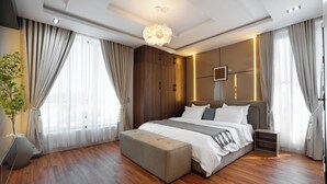 A modern bedroom with a large bed, wooden flooring, and a pendant light. - Chennad Apartment  (Abuja)