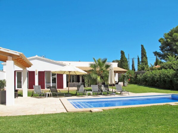Une maison moderne dotée d’une piscine, d’un espace salon extérieur et d’un jardin bien entretenu.