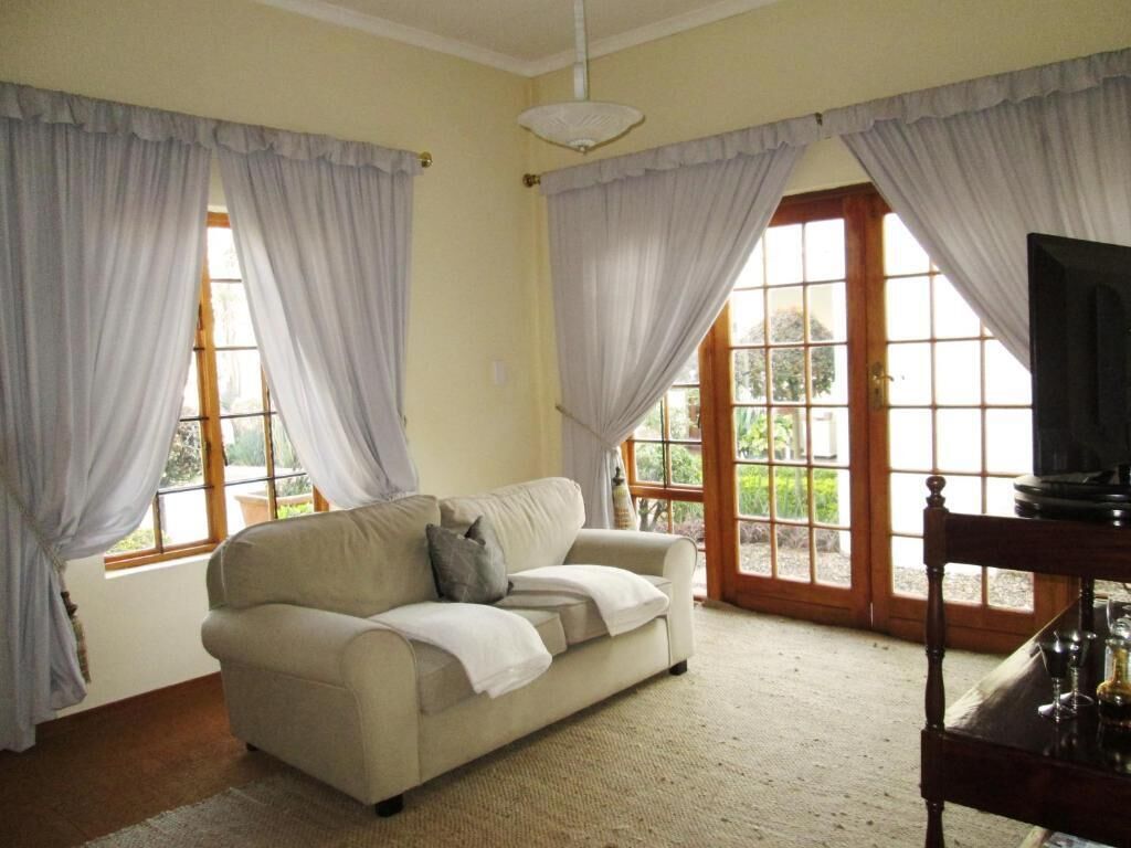 Una sala de estar con un sofá, cortinas, un televisor y vistas a través de las ventanas.