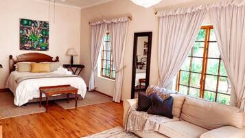 Un dormitorio con cama, mesita de noche, lámpara y vistas al exterior.