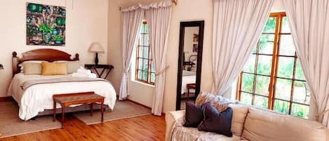 A bedroom with a bed, bedside table, lamp, and a view of the outdoors.