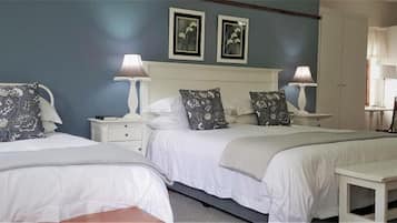 A hotel room with two beds, white bedding, and matching nightstands with lamps.